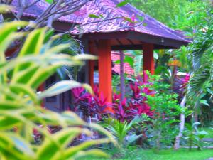 a small house in a garden with colorful plants at Suka Sari Cottages in Pemuteran