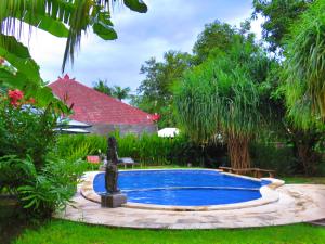 a swimming pool in a garden with a fountain at Suka Sari Cottages in Pemuteran