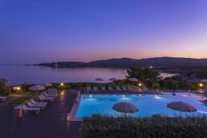 a large swimming pool with chairs and umbrellas at Hotel Dei Pini in Alghero