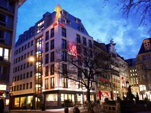 ein hohes weißes Gebäude in der Nacht auf einer Stadtstraße in der Unterkunft Eden Hotel Früh am Dom in Köln