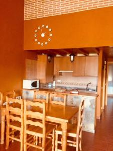 cocina con mesa y reloj en la pared en la cabaña de gredos en San Martín de la Vega del Alberche