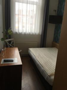 a small room with a bed and a desk and a window at Hotel Gevers in Scheveningen