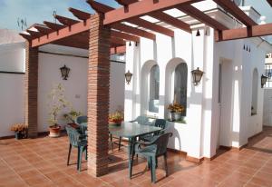 a patio with a wooden pergola and a table and chairs at Easy Nerja Apartments in Nerja