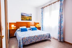 a bedroom with a bed with blue pillows and a window at Apartamentos Kasa in Las Palmas de Gran Canaria