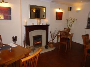 a living room with a fireplace and a table and chairs at The Manian in Kilgetty