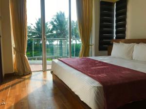 a bedroom with a large bed and a large window at Nilaveli Ocean Condos in Trincomalee