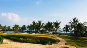 a golf course with palm trees and a path at Nilaveli Ocean Condos in Trincomalee