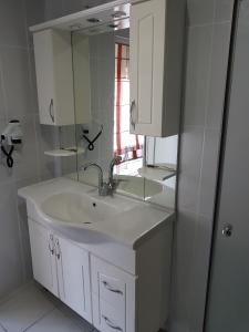 a white bathroom with a sink and a mirror at Berrak Su Hotel in Antalya