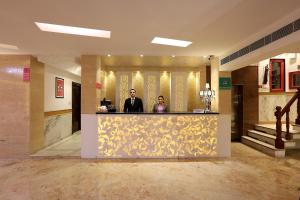 dos personas de pie en un mostrador en el vestíbulo en Hotel International Inn - Near Delhi Airport, en Nueva Delhi