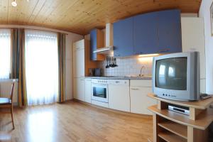 a kitchen with blue cabinets and a tv on a table at Ferienwohnung Plozner in Rattendorf