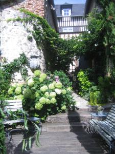 a garden with benches and flowers and a building at La Cour Sainte Catherine demeure de charme in Honfleur