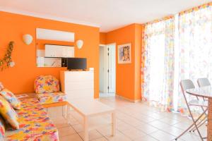 ein Wohnzimmer mit orangefarbenen Wänden und einem Tisch in der Unterkunft HUELLA CANARIA Complejo LAS OLAS in Playa del Ingles