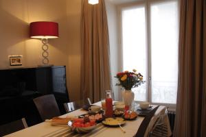 a dining room table with a vase of flowers on it at La Maison de Léa in Paris