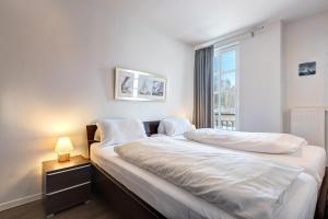 Schlafzimmer mit einem Bett mit weißer Bettwäsche und einem Fenster in der Unterkunft Residenz am Balmer See - BS 56 mit Wellnessbereich in Balm