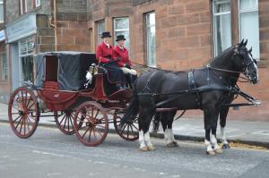 dos personas montadas en un carruaje tirado por caballos en una calle en A-Haven Townhouse Hotel, en Edimburgo