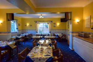 a dining room with tables and chairs and yellow walls at Eastbourne Reymar in Eastbourne