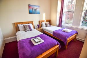 two beds in a small room with purple sheets at Eastbourne Reymar in Eastbourne