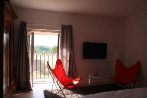 1 dormitorio con 2 sillas rojas y balcón en Les terres en Chaponost