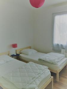 2 Betten in einem Zimmer mit einem Fenster und einer rosa Lampe in der Unterkunft à 50 mètres de la plage in Île-Tudy