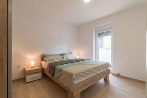 Una habitación blanca con una cama y una ventana en Apartments Mira, en Pula