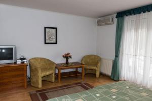 ヘーヴィーズにあるMuskátli Apartmanházの椅子2脚、テーブル、テレビが備わる客室です。