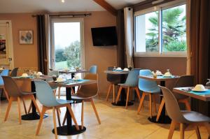 un restaurante con mesas y sillas y una ventana en Brit Hotel Azur en Saint-André-de-la-Marche