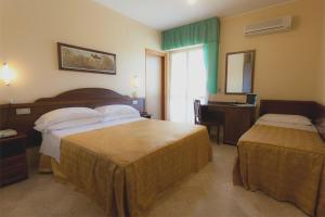 una camera d'albergo con 2 letti e una scrivania di Hotel Maria a Pineto