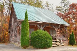 Cabaña de madera con techo verde y 2 árboles en Hartman House en Sevierville