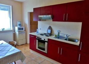 a kitchen with red cabinets and a sink and a stove at Pfaelzer Stuben in Landstuhl