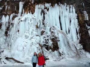 dos mujeres frente a una cascada congelada en Rodzinny Domek Apartament, en Wisłoczek