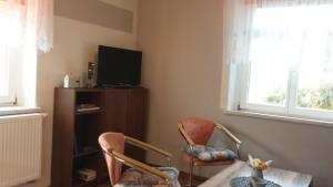 ein Wohnzimmer mit 2 Stühlen, einem Tisch und einem TV in der Unterkunft Ferienwohnung Am Elbradweg in Bad Schandau