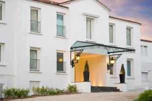 a white house with a black awning at Playas Art Hotel in Pinamar