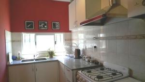 a kitchen with red walls and a stove top oven at Casa con pileta Aeropuerto Circunvalación Kempes Quorum -cambio oficial- in Cordoba