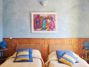 2 letti in una camera da letto con un dipinto sul muro di Les Bergeries a Tourrettes-sur-Loup