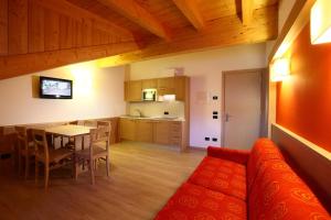 a living room with a couch and a table and a kitchen at Residence Al Lago in Auronzo di Cadore