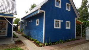 niebieski dom z białym przycinaniem obok budynku w obiekcie Błękitne domki przy morzu w mieście Międzywodzie