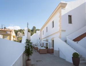 un edificio con paredes blancas y un patio con sillas en Villa Santadi en Santadi