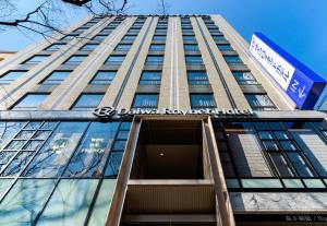a tall building with a sign on the side of it at DEL style Fukuoka Nishinakasu by Daiwa Roynet Hotel in Fukuoka