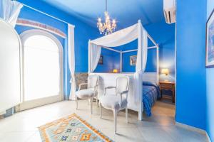 een blauwe slaapkamer met een hemelbed en stoelen bij La Locanda della Vecchia Hosteria in Gavorrano