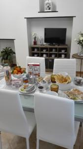 基亞瓦里的住宿－Maison Verika，一张桌子,上面有食物,上面有白色的椅子