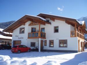 un edificio con un coche rojo estacionado en la nieve en Haus Kathrin, en Kaprun