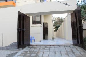 une porte ouverte menant à une maison blanche avec une chaise bleue dans l'établissement Patel Residency Guest House 2, à Karachi