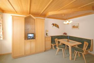 a dining room with a table and a tv at Landhaus Gensbichler in Saalbach Hinterglemm