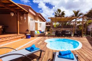 een patio met een hot tub op een houten terras bij Villa Hibiscus Centrum Corralejo Beach Private Pool Family in Corralejo