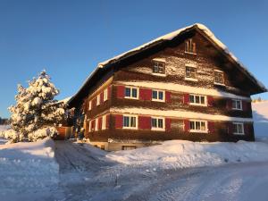 ein großes Holzhaus mit Schnee auf dem Boden in der Unterkunft Bergstätt Lodge in Immenstadt im Allgäu