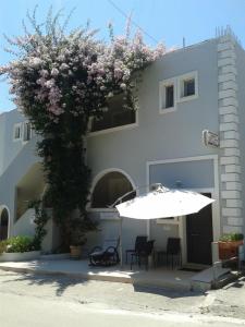 a white umbrella and chairs and a building with a tree at Anavra Studios in Syvota