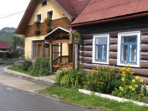 a wooden house with flowers in front of it at Chata Holica PIENINY in Lesnica