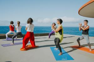 a group of people in a yoga class by the ocean at Nature Madeira Guest House in Porto da Cruz