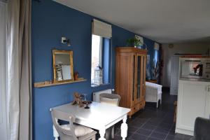 une salle à manger avec des murs bleus et une table blanche dans l'établissement Appartement De Bosuil, à Groesbeek