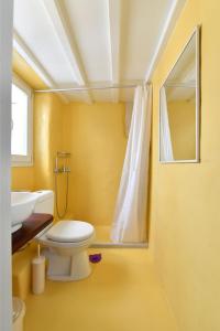 Un baño amarillo con inodoro y lavabo. en Kastro Traditional House, en Parikia
